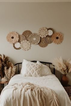 a white bed topped with lots of pillows next to a wall mounted art piece on the wall