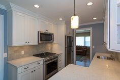 a kitchen with white cabinets and stainless steel appliances