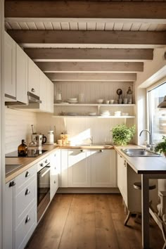 a kitchen with white cabinets and wooden floors is seen in this image, while the sun shines through the window