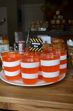 orange and white striped glasses sitting on a plate next to other food items at a party