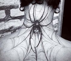 the back of a woman's neck with a spider web tattoo design on it