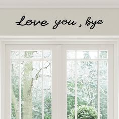 the words love you, bye are written in black on a white wall above two windows