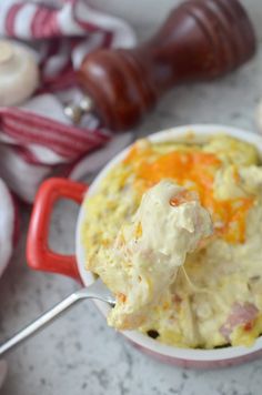 a spoon full of mashed potato salad with bacon and cheese on it next to other food items