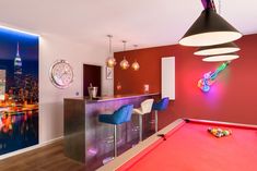 a pool table and some chairs in a room with a clock on the wall behind it