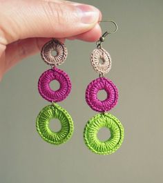 a pair of earrings is being held up by a person's hand, with two different colors