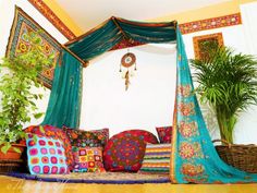 a canopy bed with colorful pillows and plants in the corner next to it on top of a hard wood floor