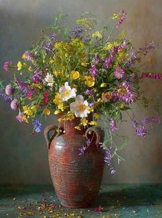 a large vase filled with lots of flowers on top of a green table next to a wall