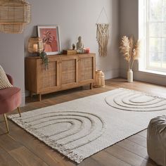 a living room with an area rug, chair and sideboard in it's center