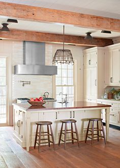 a kitchen with two stools and an island in the middle, surrounded by wooden flooring