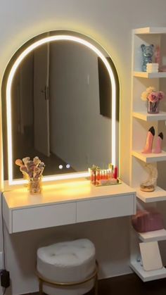 a white vanity with a lighted mirror and stool in front of it on the wall