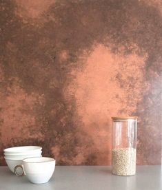 two white bowls sitting on top of a table next to a glass vase filled with sand