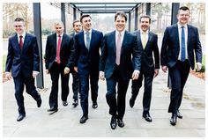 a group of men in suits and ties walking down a sidewalk