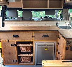 the inside of a van with wooden cabinets and drawers