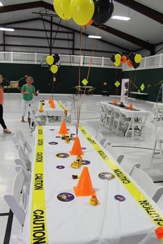 a long table with yellow and black balloons on it in an indoor event hall,