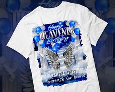 a white t - shirt with blue balloons and an image of two angel wings on it