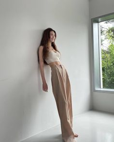 a woman standing next to a window in a room