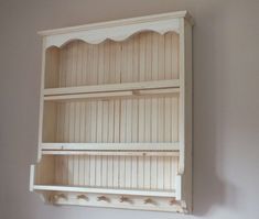 a white shelf with two shelves on top of it in the corner of a room