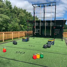 an artificial football field with foosballs and balls on the grass in front of a wooden fence