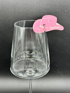 a wine glass with a pink bow on the top and a name tag attached to it