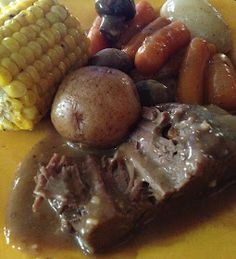 a yellow plate topped with meat, potatoes and carrots next to corn on the cob