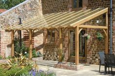 an outdoor patio area with chairs and table next to brick building that has a pergolated roof