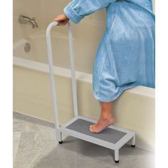 a person standing on a blue and white step stool in a bathtub with their foot propped up against the edge