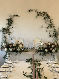 the table is set with place settings and floral arrangements on the wall behind it, along with wine glasses