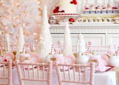 a table topped with lots of white and pink desserts next to a christmas tree