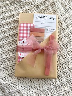 an open book with pink ribbon on it and some papers attached to the front cover