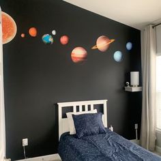 a bed room with a neatly made bed and planets on the wall