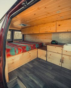 the interior of a camper van with wood paneling and storage space in it