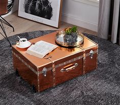 an open suitcase sitting on top of a rug next to a table with a book