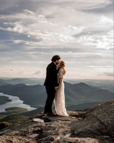 a bride and groom standing on top of a mountain