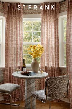 there is a vase with yellow flowers on the table and two chairs in front of it