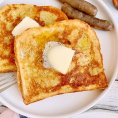 two pieces of french toast on a plate with butter and sausage