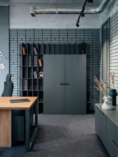 an office with gray walls and wooden desks next to a bookcase filled with books