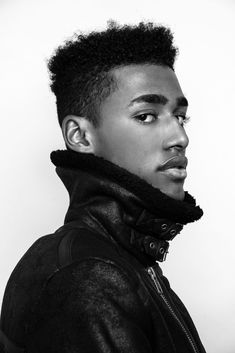 a black and white photo of a young man with an afro haircut wearing a leather jacket