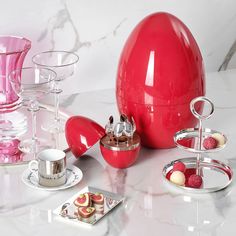 an egg shaped object on a table with other objects around it and plates, cups, saucers and spoons