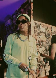 a man with dreadlocks standing in front of a wall