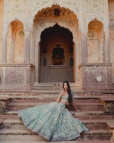 a woman in a blue dress sitting on some steps