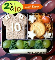 a lunch box with grapes, broccoli and crackers in the shape of a football jersey