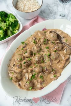 a white bowl filled with mushrooms and broccoli on top of a pink table cloth