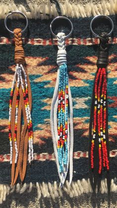 three beaded key chains hanging from hooks on a rug