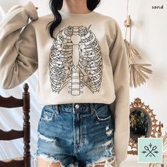 🌟 Want 10% off this item?? Join our email list here! https://www.alura.io/subscribe?=SpoonieSisterShop  Floral ribcage sweatshirt, featuring delicate flowers paired with a cool vintage-inspired anatomy design! Perfect for chronic illness warriors, physical therapists, med students, and overall anatomy lovers! Comfy, unisex relaxed fit sweater that's flattering for everyone. DETAILS: * Made to order * Unisex adult sizing (size chart in photos) * 50% Cotton, 50% Polyester * Machine wash cold with like colors, hand dry or tumble dry low 🌿 Cute coordinating Floral Ribs Anatomy T-Shirt available here: https://spooniesistershop.etsy.com/listing/1757002107 If you have any questions regarding this listing, please hit the "Ask a Question" button next to the price, and I will get back to you withi Ribcage Sweatshirt, Ribs Anatomy, Slipping Rib Syndrome, Floral Ribcage, Skeleton Ribs, Anatomy Design, Spoon Theory, Delicate Flowers, Cool Vintage