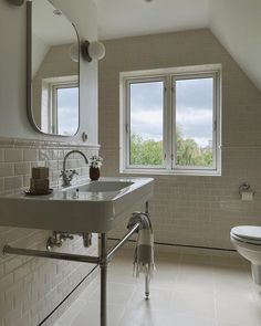 a bathroom with a sink, toilet and window in the wall next to it is white tile