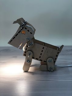 a wooden toy horse made out of metal parts on a wood table with light coming from behind it