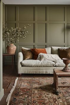 a living room filled with furniture and walls covered in green paneled wallpapers