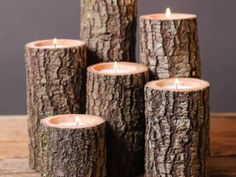 four wooden logs with lit candles in them