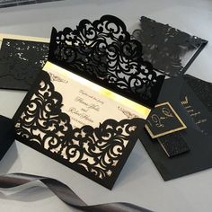 some black and gold wedding cards on a table