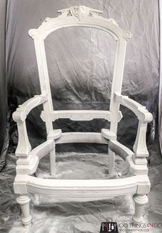 a white painted bed frame sitting on top of a sheet covered floor next to a gray wall